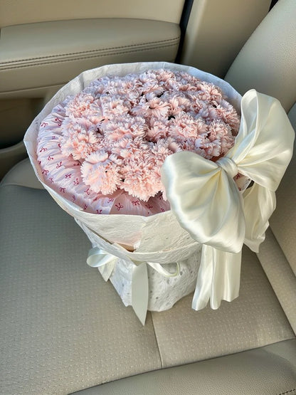 Blush Carnation Grand Bow Bouquet, Medium, high-angle car-seat view; AI lifestyle illustration