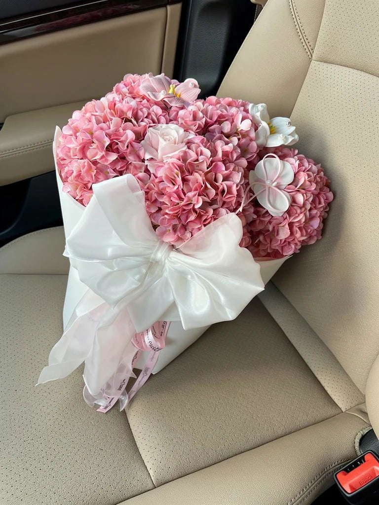 High-angle view of Blush Reverie Pink Silk Hydrangea Bouquet on a parked-car passenger seat; AI lifestyle illustration