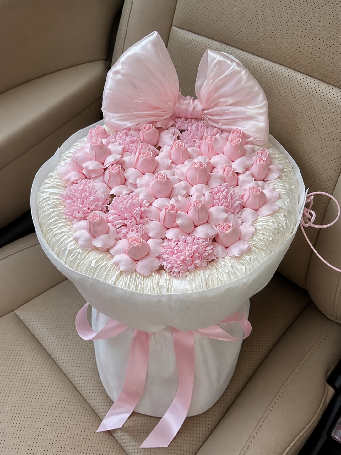 Pink Rosebud Bow Celebration Bouquet – the pictured pink rosebud and carnation design; size is illustrative – AI-assisted high-angle parked car view