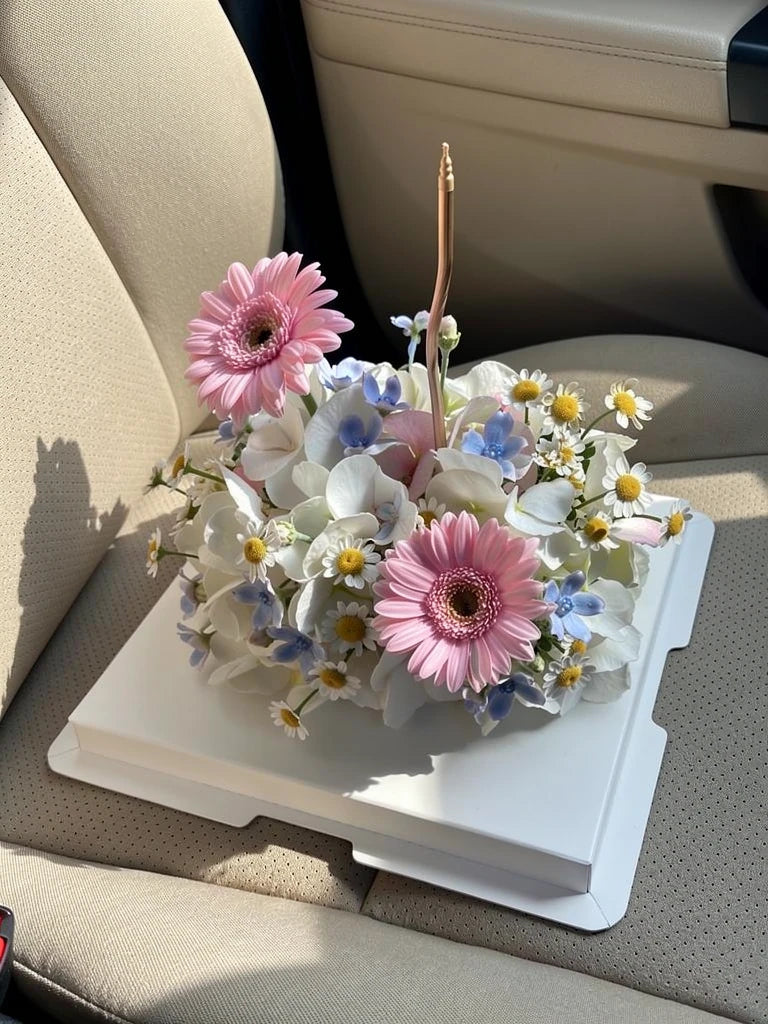 Pink Daisy Ivory Flower Cake, Medium, high-angle car-seat view; AI lifestyle illustration