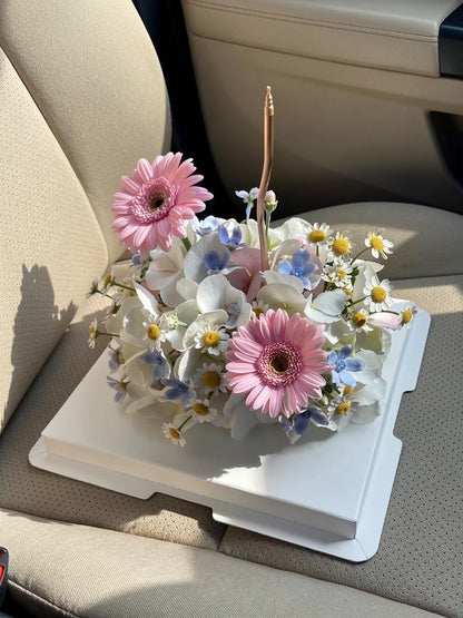 Pink Daisy Ivory Flower Cake, Medium, high-angle car-seat view; AI lifestyle illustration